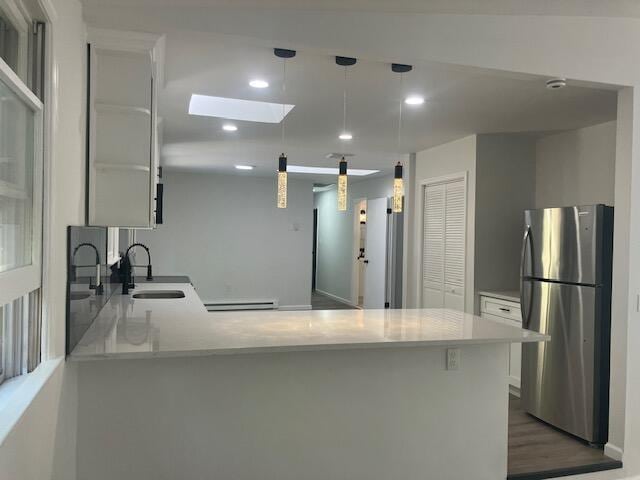 3354 Trafalgar Ave, East Stroudsburg, PA 18302 - kitchen with freestanding refrigerator, a skylight, recessed lighting, white cabinetry, and a peninsula
