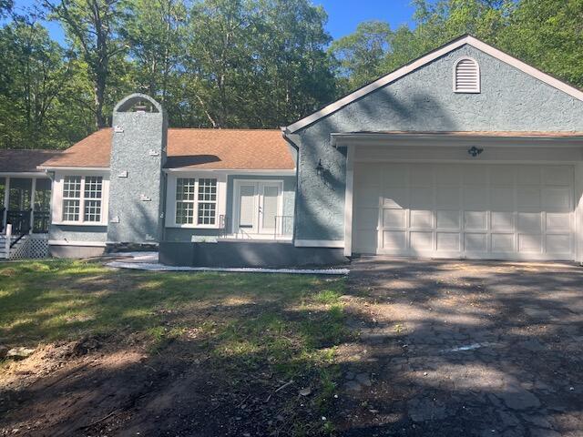 3354 Trafalgar Ave, East Stroudsburg, PA 18302 - view of property exterior featuring an attached garage, asphalt driveway, a chimney, and french doors