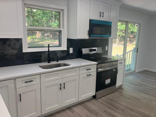 3354 Trafalgar Ave, East Stroudsburg, PA 18302 - kitchen with black microwave, stainless steel range with electric cooktop, white cabinets, and light wood finished floors