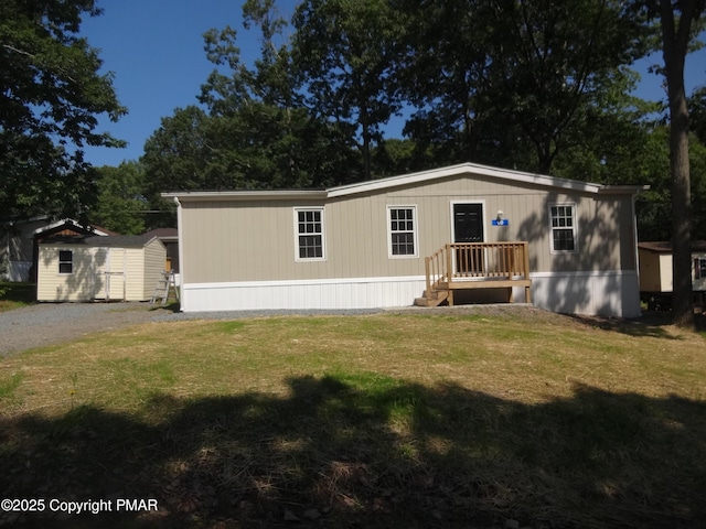 manufactured / mobile home featuring a shed, a front lawn, and an outdoor structure