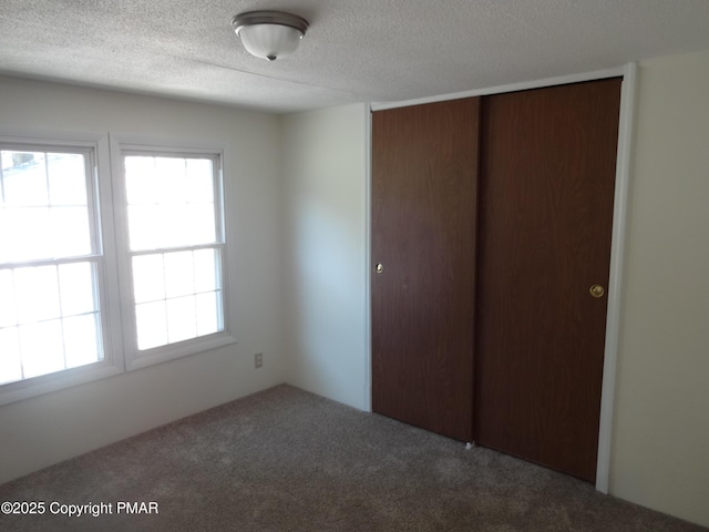 unfurnished bedroom with carpet, a closet, and a textured ceiling