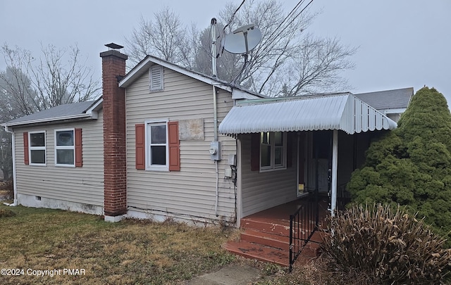 view of property exterior featuring crawl space, a chimney, and a lawn