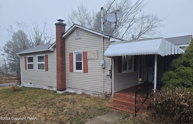 view of side of home featuring crawl space, a yard, and a chimney