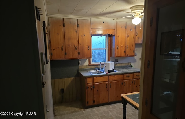 kitchen featuring brown cabinetry, a sink, and a ceiling fan