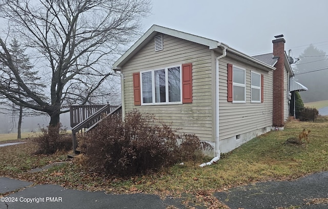 view of property exterior featuring crawl space and a chimney