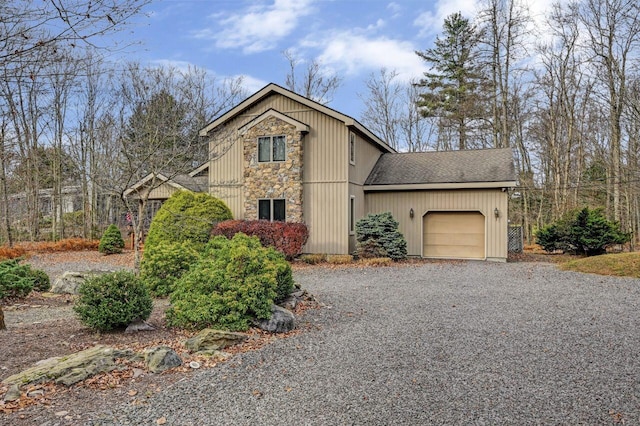traditional-style house featuring an attached garage, driveway, a shingled roof, and stone siding