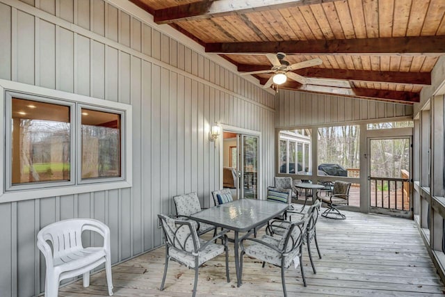 sunroom featuring a ceiling fan, outdoor dining space, and beam ceiling