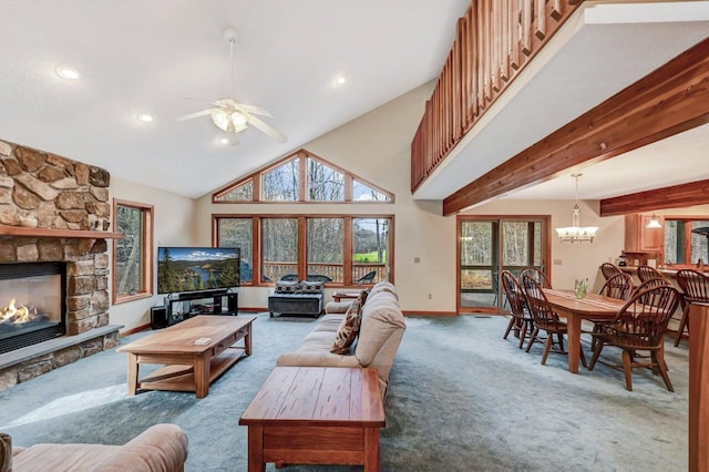 carpeted living room with baseboards, a stone fireplace, ceiling fan with notable chandelier, and plenty of natural light