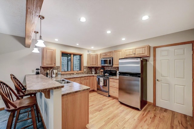 kitchen featuring stainless steel appliances, a peninsula, a sink, and light brown cabinets