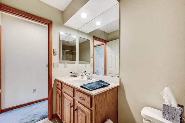 bathroom with vanity, recessed lighting, baseboards, and toilet