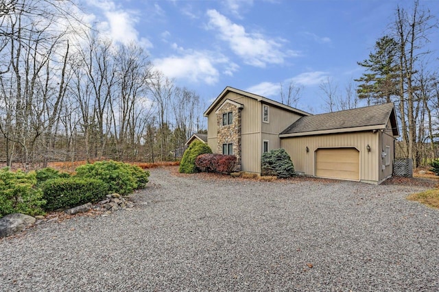 view of front of property featuring driveway, a shingled roof, and a garage