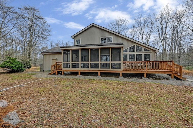 rear view of property with a wooden deck, a shingled roof, and a sunroom