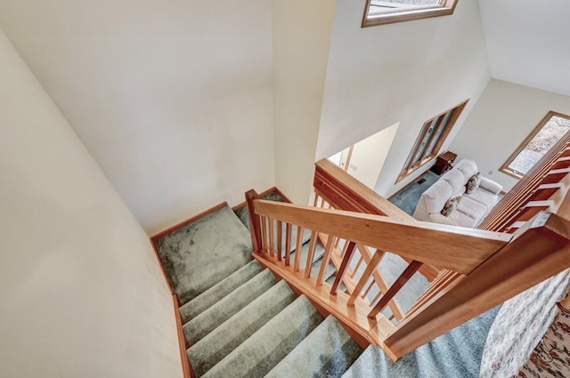 staircase with carpet and a towering ceiling