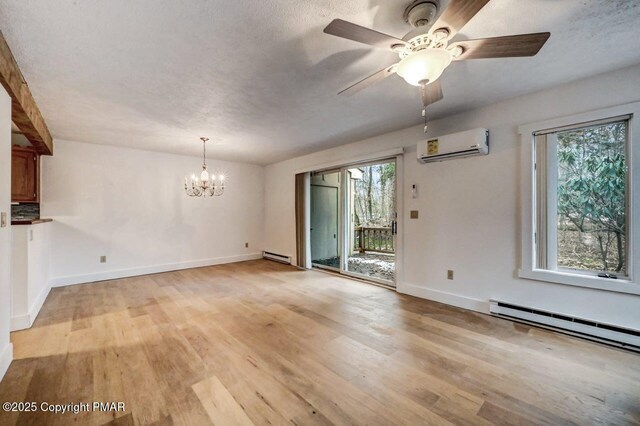 empty room featuring a baseboard radiator, ceiling fan with notable chandelier, a wall mounted air conditioner, and light hardwood / wood-style flooring