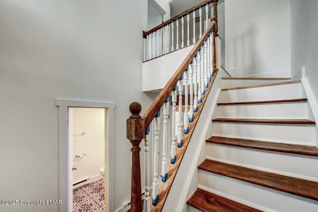 stairs with a baseboard radiator and a high ceiling