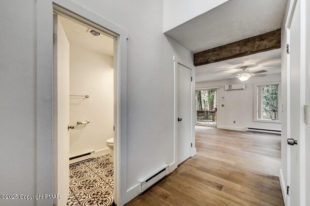 hall featuring a baseboard heating unit, beam ceiling, and light hardwood / wood-style floors