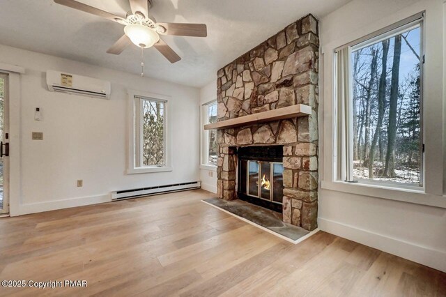 unfurnished living room with a stone fireplace, light wood-type flooring, a wall mounted air conditioner, and baseboard heating