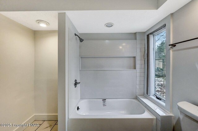 bathroom with tiled shower / bath, tile patterned floors, and toilet