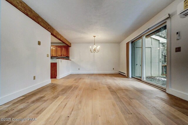 unfurnished living room with an AC wall unit, light wood-type flooring, an inviting chandelier, and baseboard heating