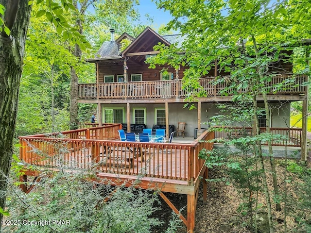 rear view of property featuring a shingled roof and a wooden deck