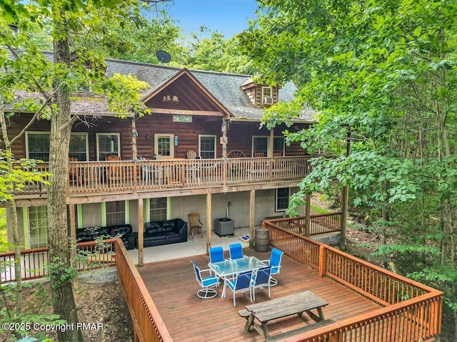 rear view of house featuring a deck, outdoor dining space, central AC unit, and a shingled roof