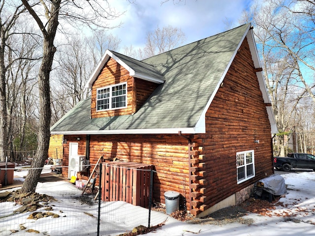 snow covered property with log exterior and roof with shingles