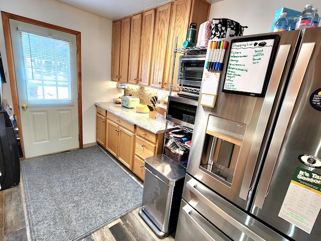 kitchen featuring a toaster, stainless steel appliances, light wood-type flooring, decorative backsplash, and light stone countertops