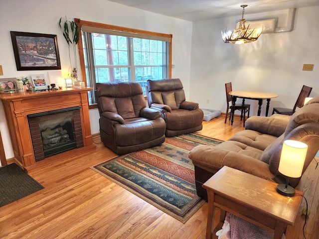 living room with light wood-style floors, a fireplace, and a notable chandelier