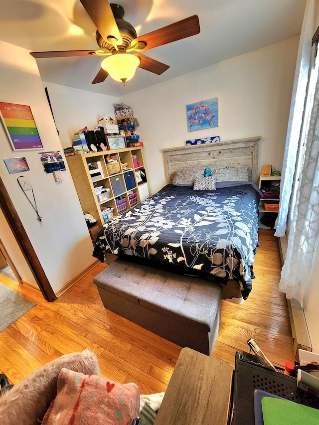 bedroom featuring a ceiling fan, baseboards, and wood finished floors