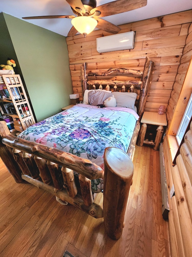 bedroom with ceiling fan, hardwood / wood-style floors, and a wall mounted air conditioner