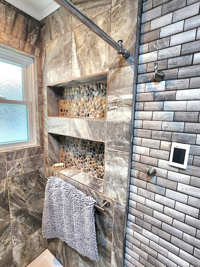 bathroom featuring ornamental molding and tiled shower