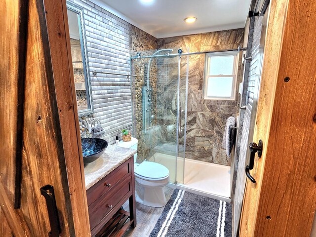 full bath with toilet, a shower stall, wood finished floors, and vanity