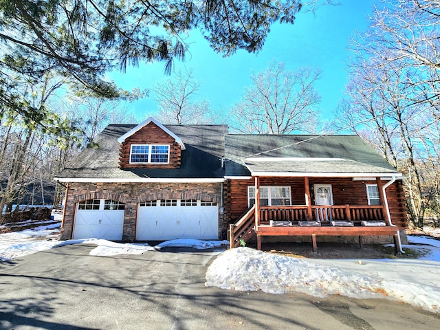 log-style house featuring a porch, stone siding, driveway, and log exterior