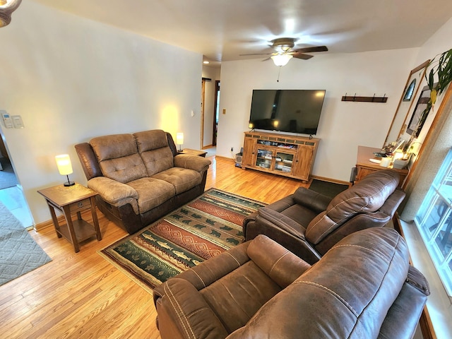 living room with baseboards, a ceiling fan, and light wood-style floors