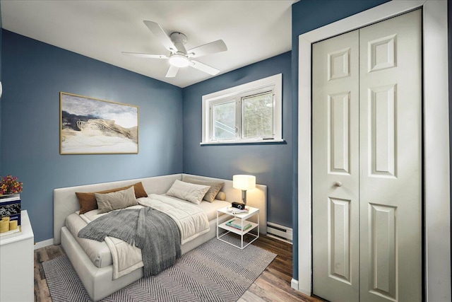 bedroom featuring a ceiling fan, a baseboard radiator, baseboards, and wood finished floors