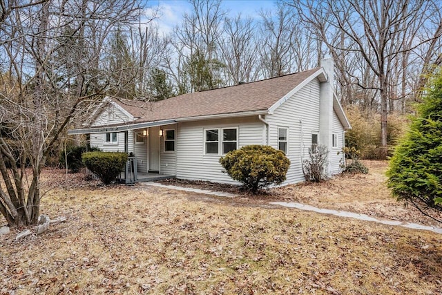 ranch-style house with roof with shingles and a chimney