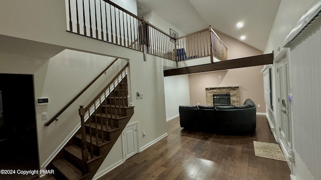 staircase featuring a fireplace, wood-type flooring, and high vaulted ceiling