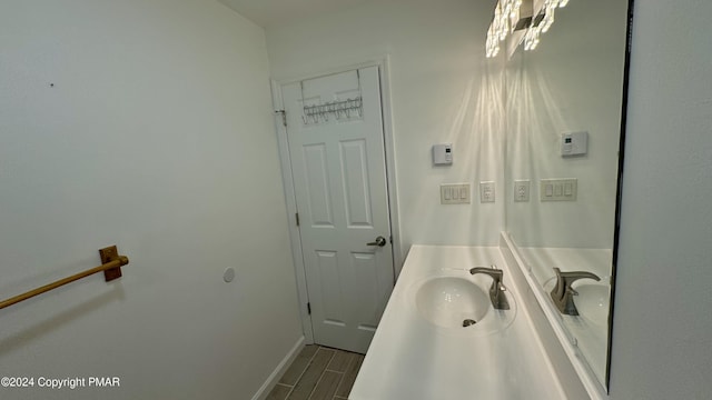 bathroom featuring wood finish floors, baseboards, and a sink