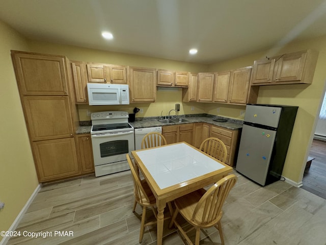 kitchen with sink, light brown cabinetry, white appliances, and light hardwood / wood-style floors