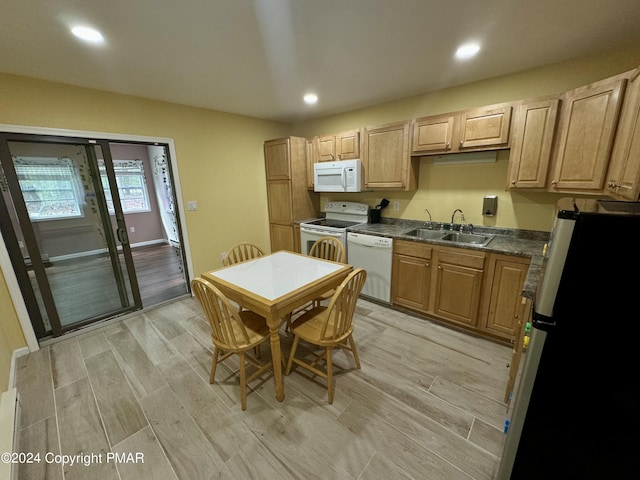 kitchen with sink, light brown cabinetry, white appliances, and light hardwood / wood-style floors