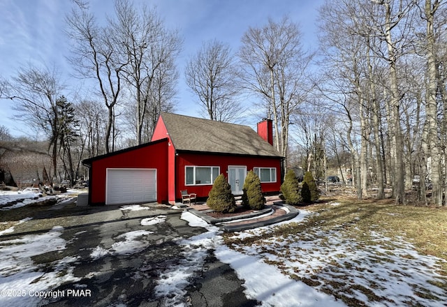 view of snowy exterior featuring driveway and a chimney