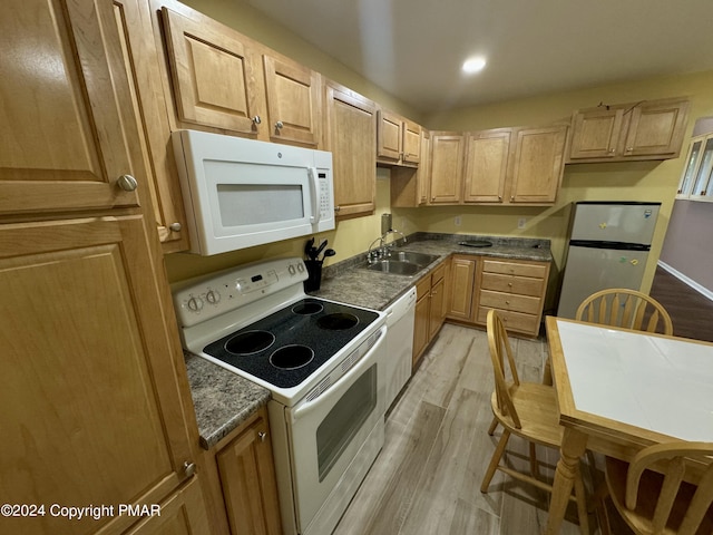 kitchen featuring sink, light hardwood / wood-style flooring, dark stone countertops, light brown cabinets, and white appliances