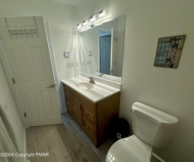 bathroom featuring wood finish floors, toilet, and vanity