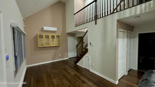 interior space featuring baseboards, stairs, wood finished floors, high vaulted ceiling, and a wall mounted AC