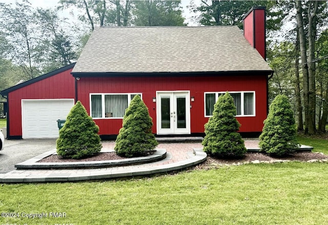 view of front of house with french doors, a shingled roof, driveway, and a front lawn