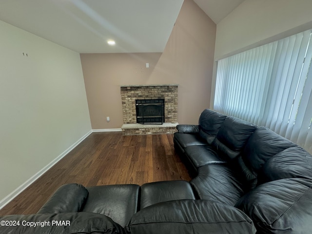 living room featuring lofted ceiling, a fireplace, and wood-type flooring