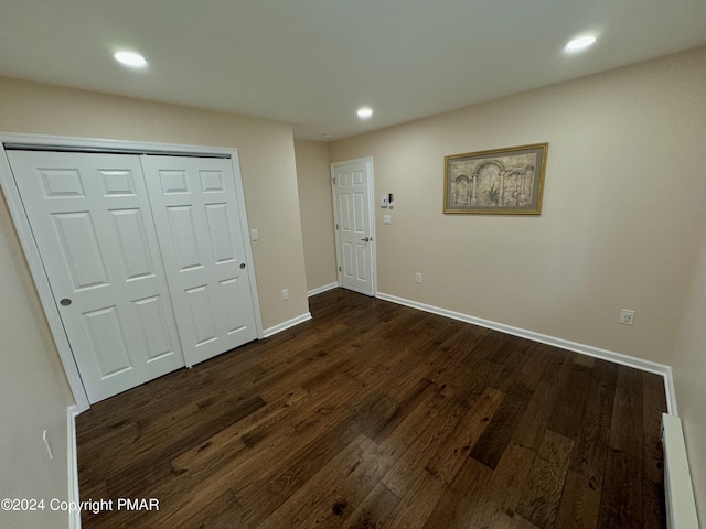 interior space with a baseboard heating unit and dark hardwood / wood-style flooring