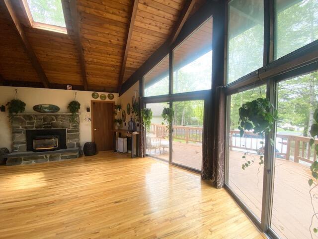 106 Palomino Ln, Lords Valley, PA 18428 - unfurnished living room with high vaulted ceiling, wood finished floors, wooden ceiling with exposed beams, healthy amount of natural light, and a fireplace