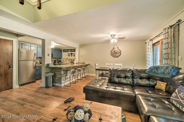 living area featuring wood finished floors, baseboards, and ceiling fan