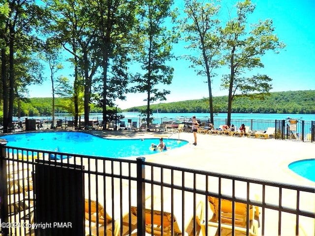 community pool with a patio area and fence